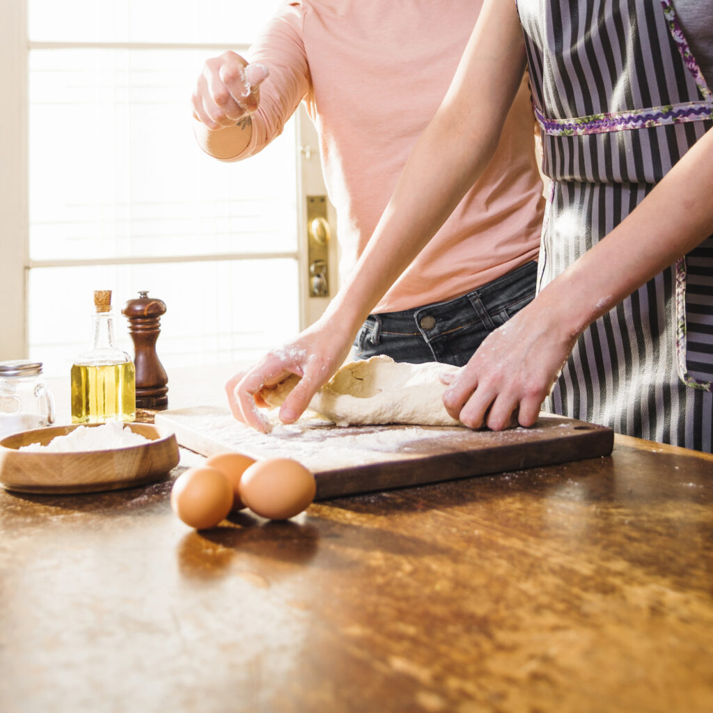 close up two female friends preparing dough chopping board (1)
