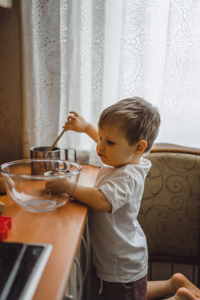 little boy in the kitchen helps mom to cook. the child is involv