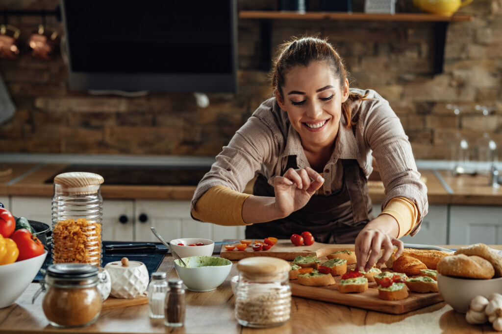 happy woman enjoying while preparing bruschetta in the kitchen.